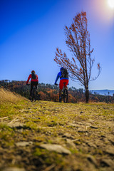 Fototapeta na wymiar Cycling, mountain biker couple on cycle trail in autumn forest. Mountain biking in autumn landscape forest. Man and woman cycling MTB flow uphill trail.