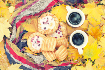 Autumn still life, two mugs with tea in hands, cakes, picnic in autumn park