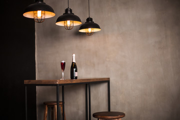 Interior photography. A bottle of wine and a glass stand on a wooden table in the restaurant hall.
