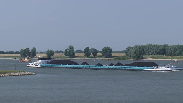 Coal ship upstream on the river Waal + dredger Dintel deepening the fairway. THE NETHERLANDS - JULY 2015: