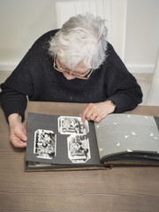 Elderly woman looking through old photographs. Shot from above