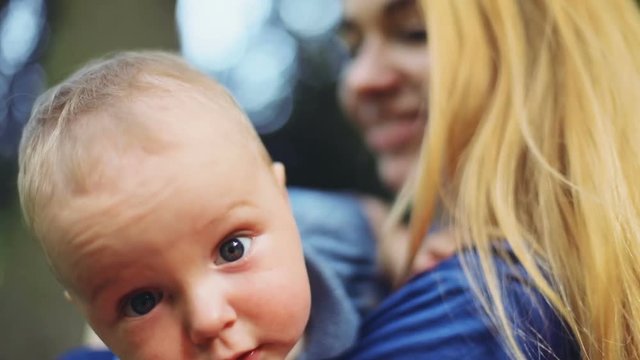 One year old baby boy lying sitting mother hands outside green nature blur background hands holding looking camera interest expression emotional face portrait calm chubby cheeks cute child son woman