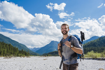 Germany, Bavaria, portrait of young hiker with backpack and hiking poles