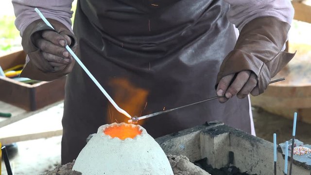 4K video footage of reenactment of ancient times. Process of making glass beads on the fire. Manufacturer of jewelry