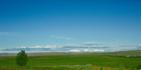Travel to Iceland. Beautiful Icelandic landscape with green fields mountains, sky and clouds.