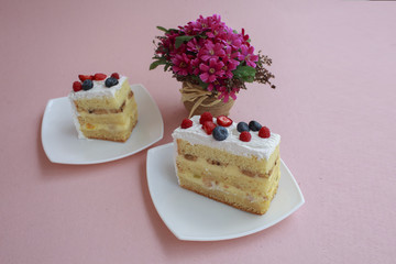 a piece of cake with blueberries and raspberries is on the table with a pink color