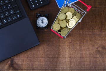 Shopping trolley with coins,  laptop and alarm clock