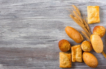 Fresh bread and wheat on wooden table. Top view with space for your text