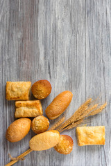 Fresh bread and wheat on wooden table. Top view with space for your text