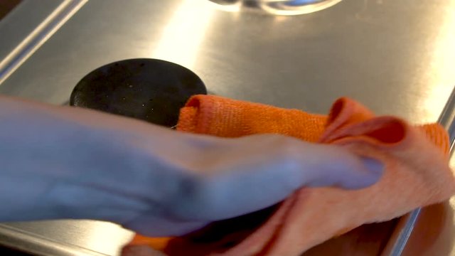 Female hand is polishing the clean steel gas-stove with microfiber for the shiny effect