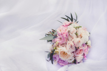 A wedding bouquet of asters and dahlias and roses on a snow-white dress on a sunny day close-up