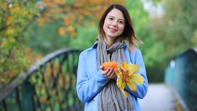 Young redhead girl with leaves and pumpking in park