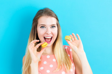 Happy young woman holding macarons on a blue background