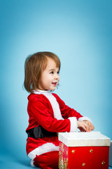 Happy toddler girl in a Santa costume with a gift box