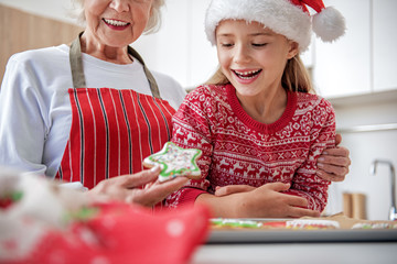 Joyful child eating cookie baked by her granny