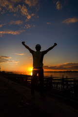 Fototapeta premium Concept of success and freedom with a young engineer holding his arms up in the sunset. engineer working on building site.