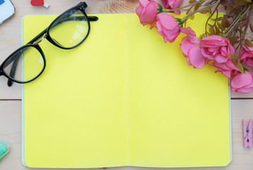 Top view of Creative writing concept with notebook,glasses and pink rose on wood background. Copy space for text.Blank area for text or message