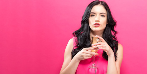 Young woman holding a champagne flute on a solid background