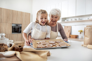 Happy senior woman enjoying baking process with her granddaughter