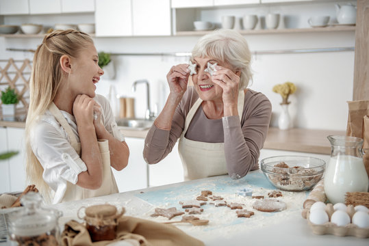 Happy granny rejoicing her granddaughter in kitchen
