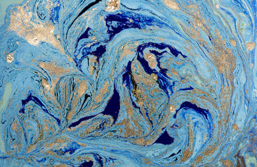 Marbled blue abstract background with golden sequins. Liquid marble ink pattern.