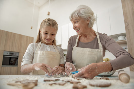 Happy granny enjoying baking process with her granddaughter