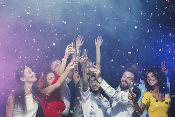 Fototapeta na wymiar Group of young people celebrating new year with champagne at night club