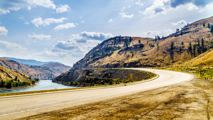 The Trans Canada Highway winding through the mountains and along the Thompson River between the...