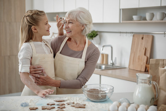 Happy granddaughter cooking pastry with her grandmother