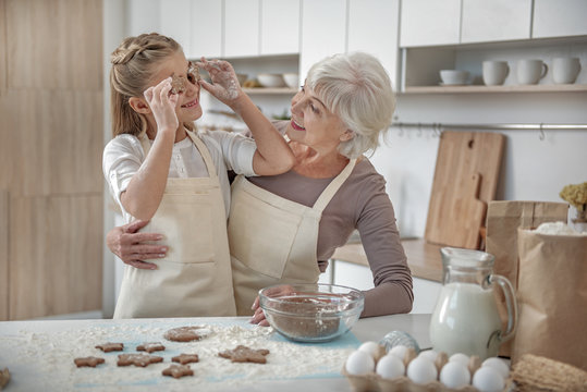 Carefree child enjoying baking process with her grandmother