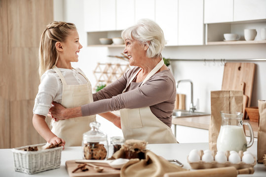 Cheerful girl entertaining with grandmother in kitchen