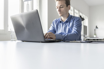 Businessman in office typing information on laptop computer