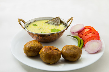 Tradtional Rajsthani food Kadi Bati or Dal Bati served with salads - tomato, onion and green chilli