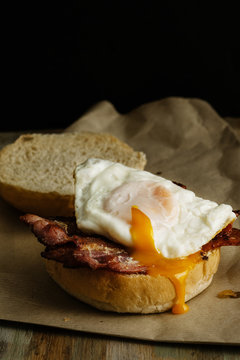Crispy bacon and a soft fried egg on a bun. Side view.