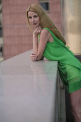 
Beautiful blonde girl in a green short summer dress on the streets of the city
