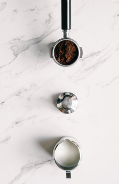 coffee group head with ground coffee, tamper and milk jug