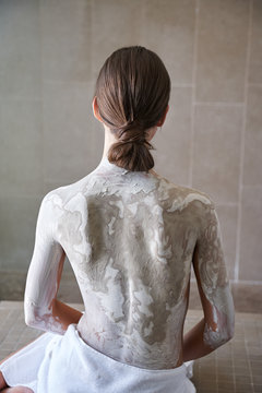 Woman doing mud bath treatment at spa