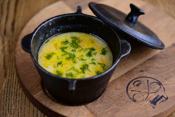 Vegetable soup on a meat broth in a cast-iron pan on a rustic background.
Useful and tasty food. Original serving of a traditional dish.