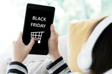 Woman hand using tablet with black Friday sale on screen device background for mock up, template, technology and lifestyle concept