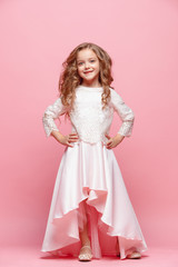 Full length of beautiful little girl in dress standing and posing over white background
