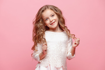 The beautiful little girl in dress standing and posing over white background