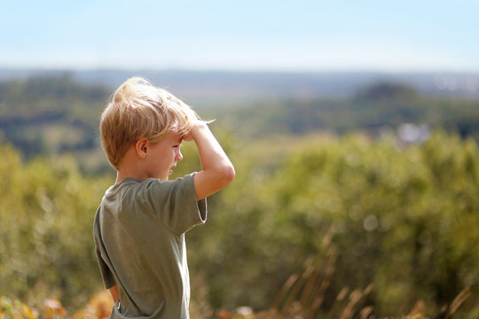 Little Boy Outside on Hike Looking out over Trees on Bluff
