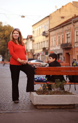 A pregnant woman walking in the city with eldest son