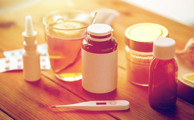 drugs, thermometer, honey and cup of tea on wood