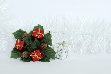 Des feuilles vertes et des cadeaux rouge sur un fond blanc avec une guirlande blanche pour les fêtes