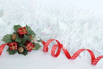 Une guirlande blanche brillante givrée avec un ruban rouge et des feuilles vertes,des cadeaux rouges sur fond blanc pour décoration de fêtes