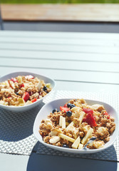 plates with fresh fruit salad, Granola and berries in the morning on the veranda. Delicious, quick and healthy light breakfast for energetic people