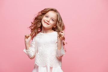 The beautiful little girl in dress standing and posing over white background
