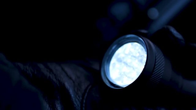 Experienced thief lighting flashlight preparing to crack lock and commit robbery