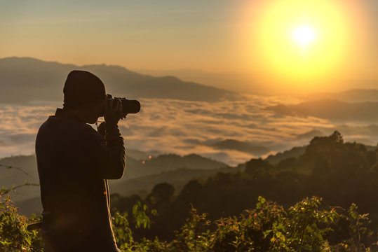 Photograph takes photos of daybreak above heavy misty valley. Landscape view of misty autumn mountain hills and hiker silhouette